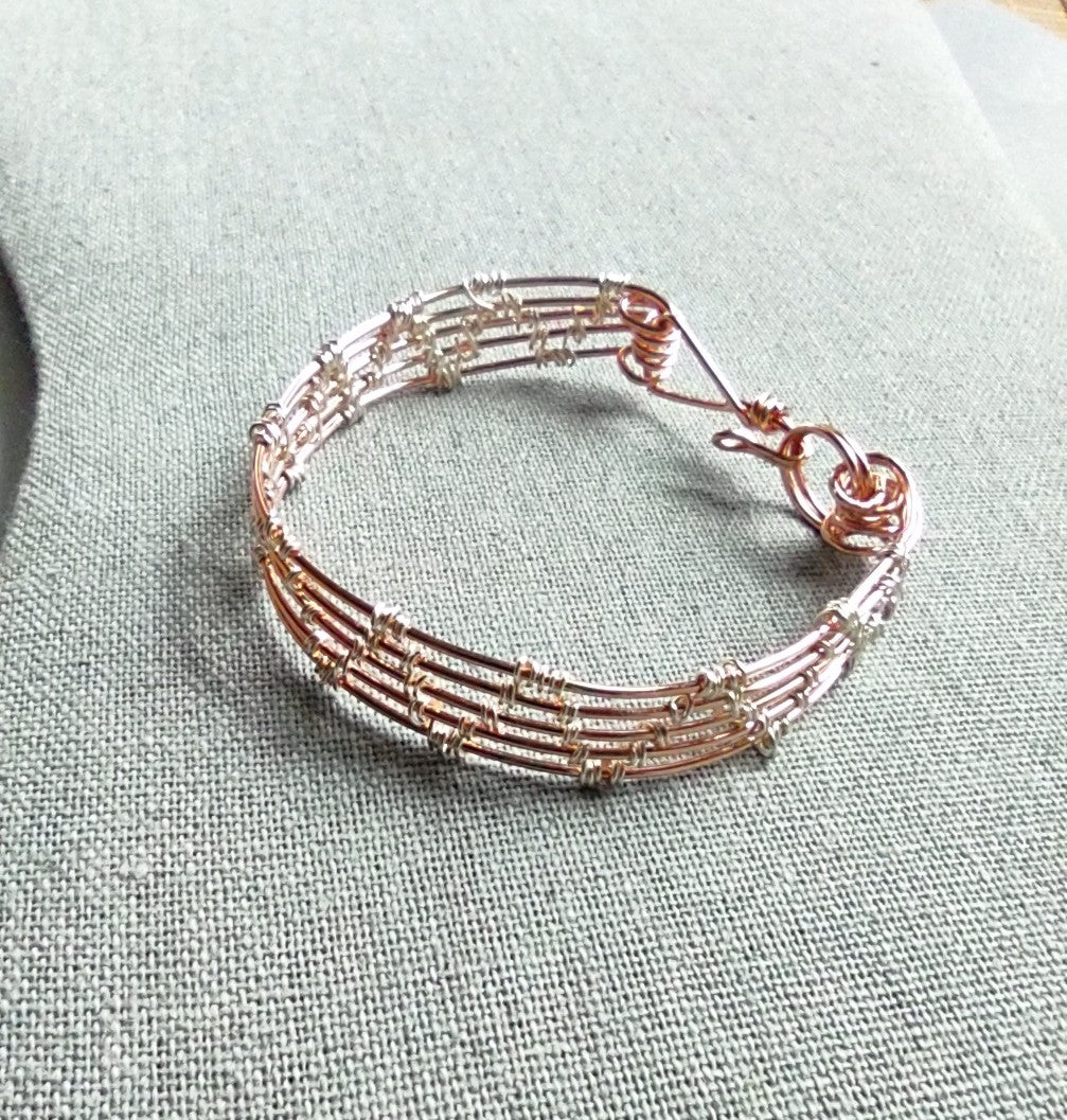 A multi-strand copper wire bracelet with small silver bead accents, displayed on a textured light gray fabric background.
Details

JPG

• 1007 × 1057

• 399.48 kB