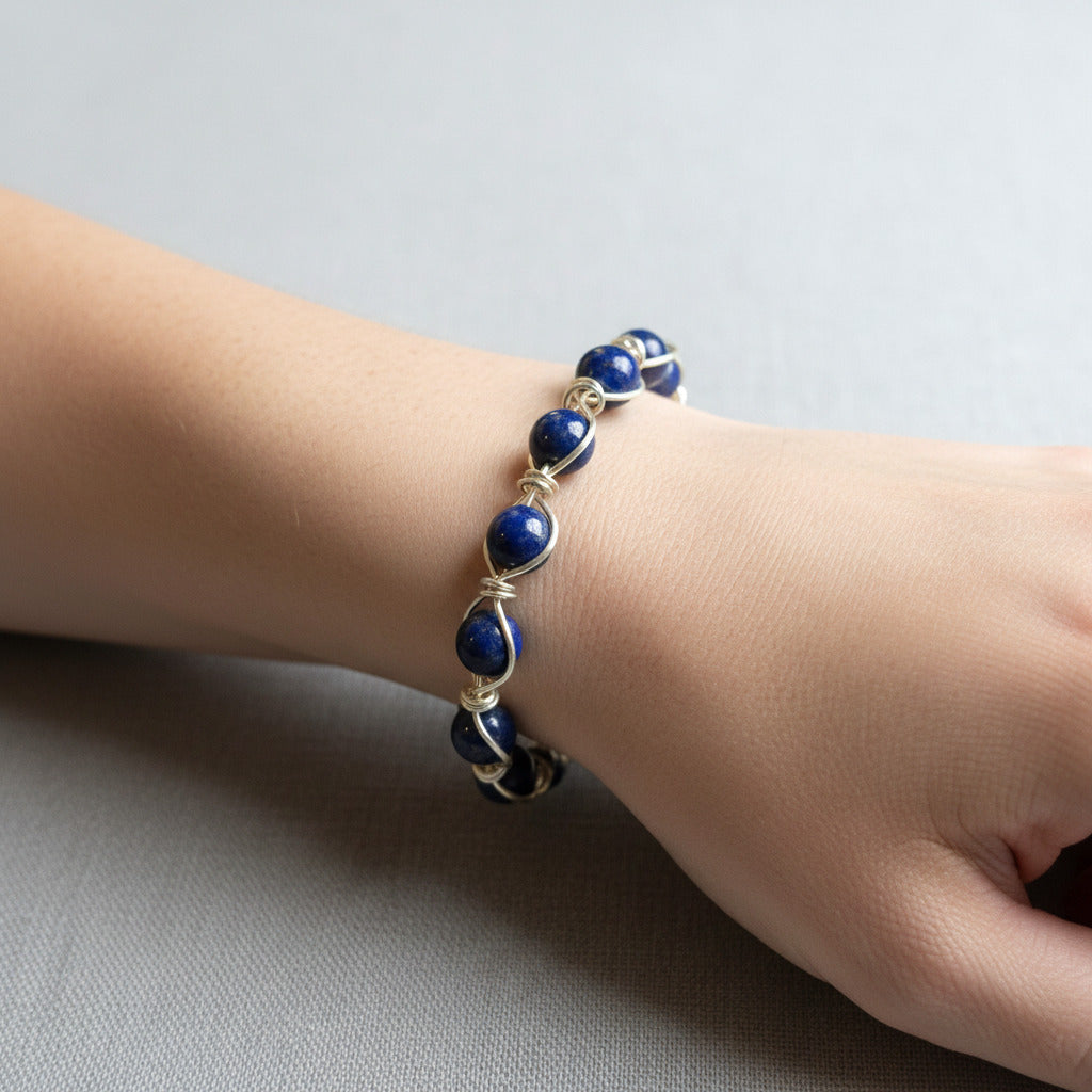 A hand made circular wire wrapped bangle bracelet featuring lapis lazuli beads. 
