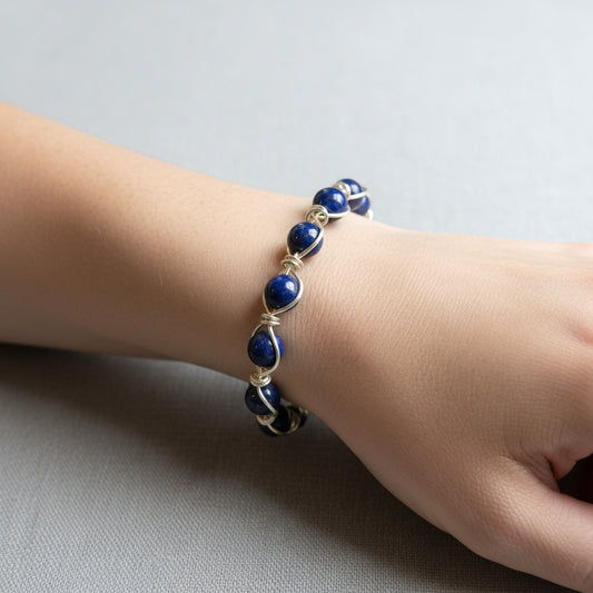 A hand made circular wire wrapped bangle bracelet featuring lapis lazuli beads. 